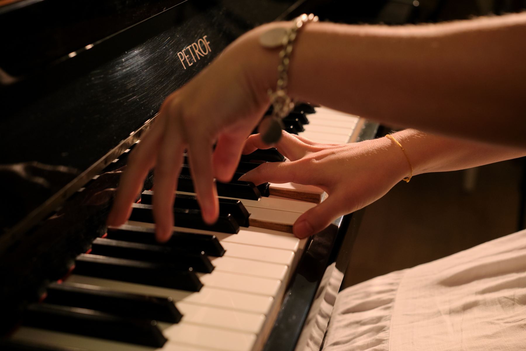 Deux mains sur le clavier d’un piano Petrof